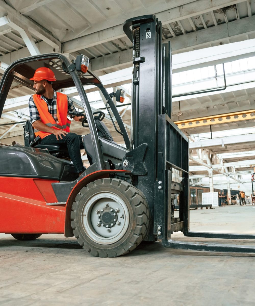 Driving the forklift. Industrial worker in wooden warehouse.